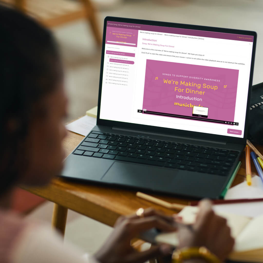 unrecognisable woman sitting in front of a laptop that is displaying a course while she is making notes